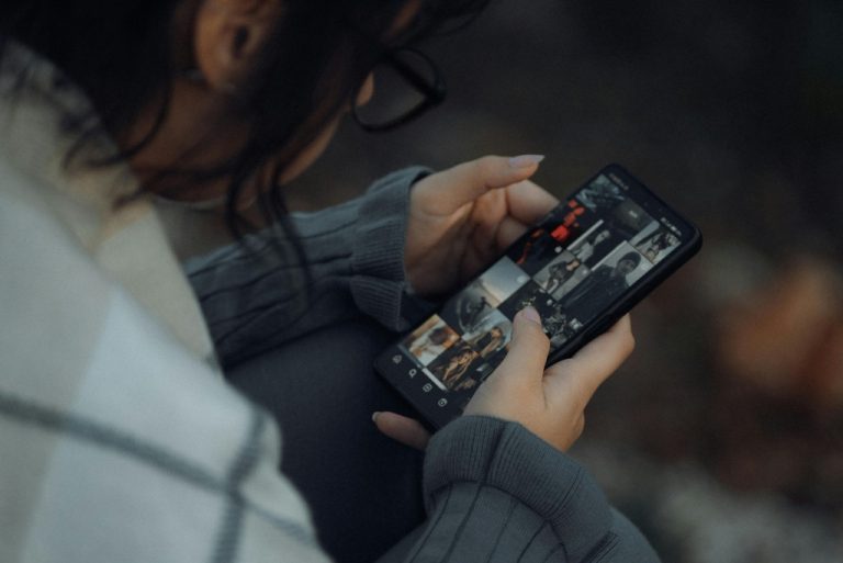 A woman looks at a social media page on her phone.