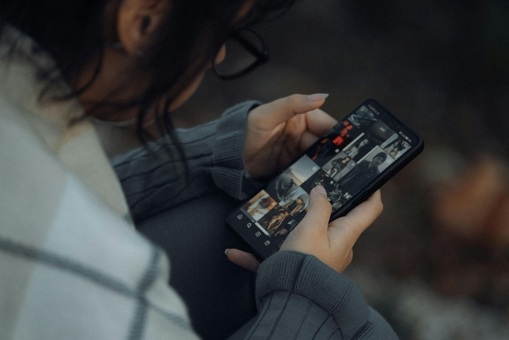 A woman looks at a social media page on her phone.